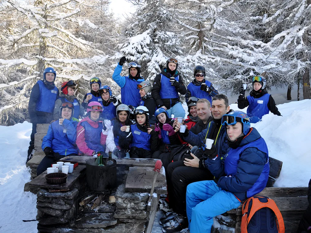 Große Gruppe sitzt an den Tischen der Skihütte.